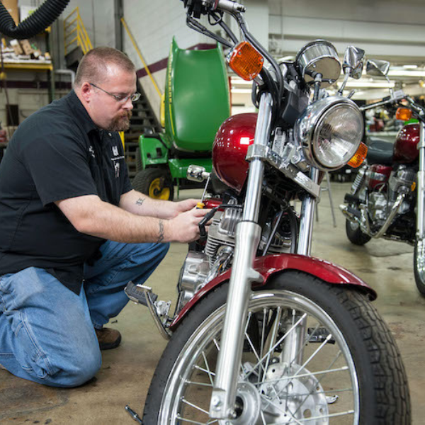 Worker inspecting or tightening lug nuts on a large truck wheel.