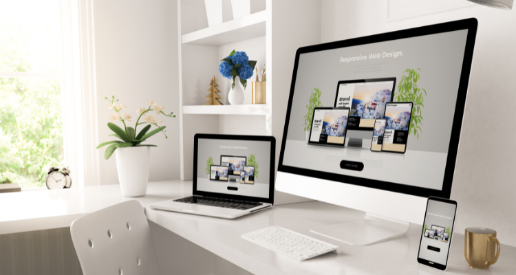 Workspace showing a desktop computer, laptop, and smartphone displaying a responsive web design layout