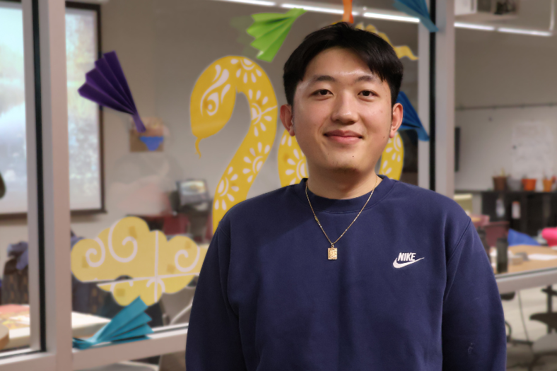 Student, Jordan Vang, poses with his graphic design portfolio.